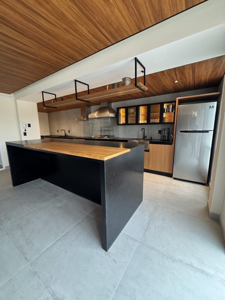 Ilha de cozinha em pedra escura com bancada lateral